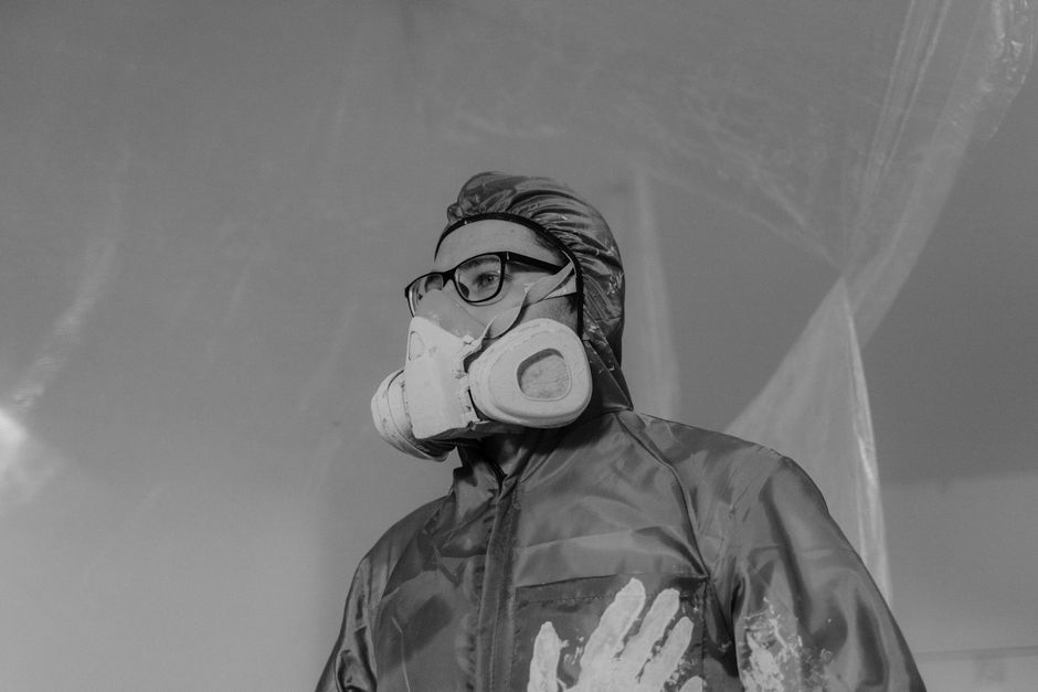 Worker wearing a gas mask and safety gear in a monochrome setting, emphasizing protection and safety.