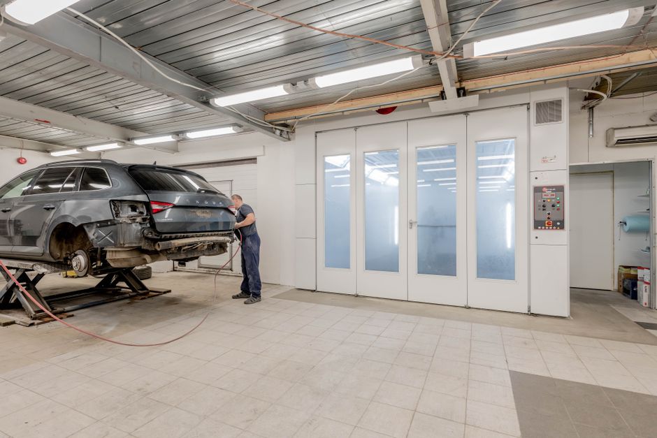 Mechanic repairing a car indoors at an auto workshop, focusing on vehicle maintenance.