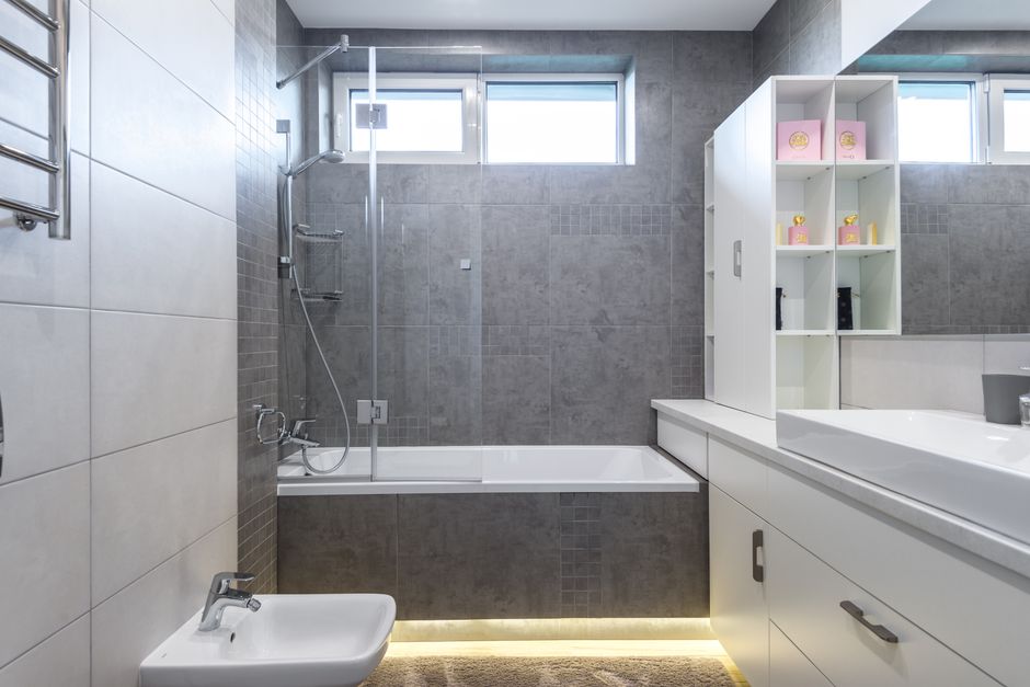 Contemporary bathroom featuring sleek gray tiles, bathtub, shower, and vanity.