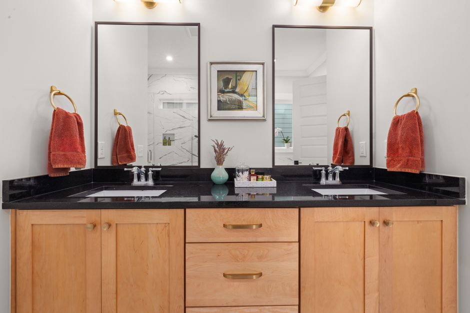 Elegant bathroom vanity featuring dual sinks, black countertop, and mirrors.