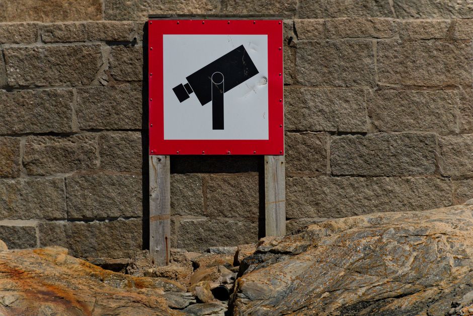 A bold CCTV warning sign on a rugged stone wall, emphasizing security and surveillance.