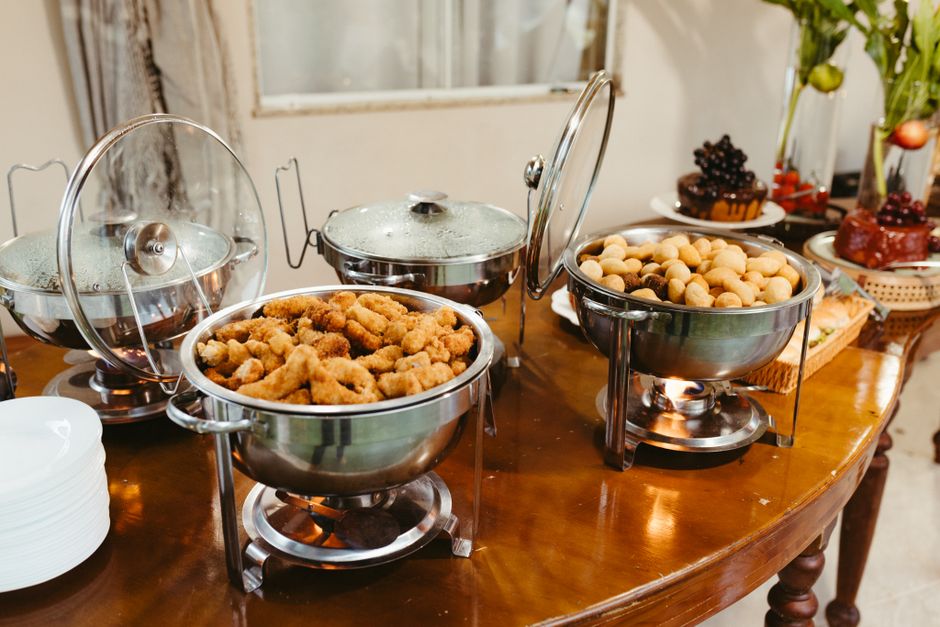 Delicious buffet spread featuring assorted appetizers in chafing dishes on a wooden table.