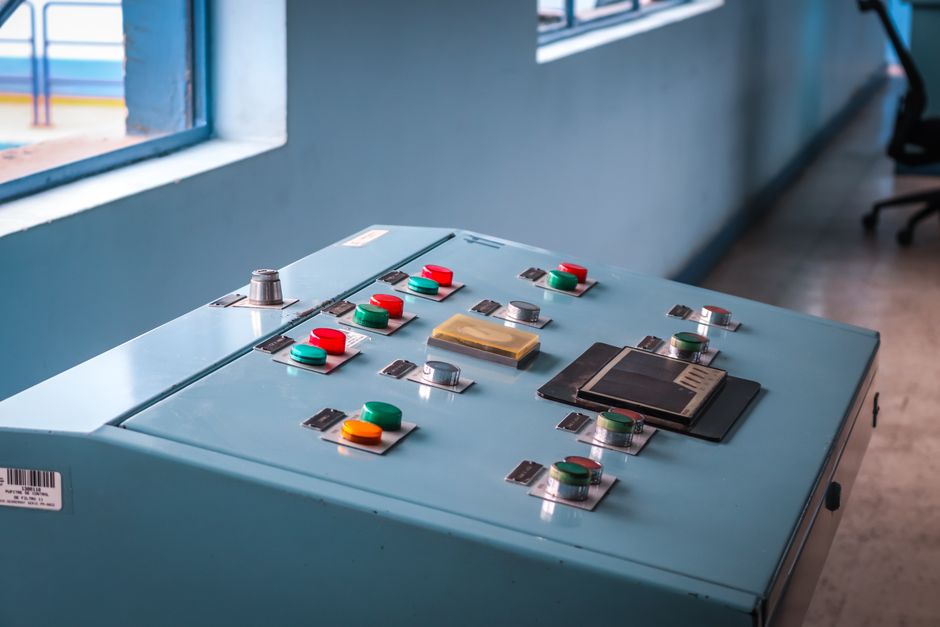 Close-up of an industrial control panel with colorful buttons in a factory setting.