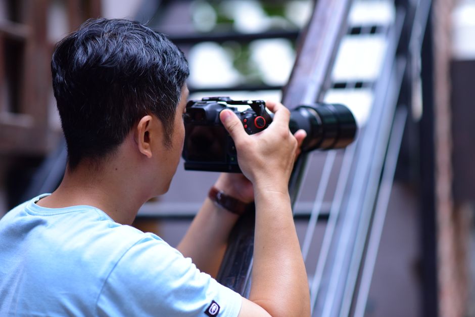 Man using camera outdoors in modern setting, capturing creative shots.