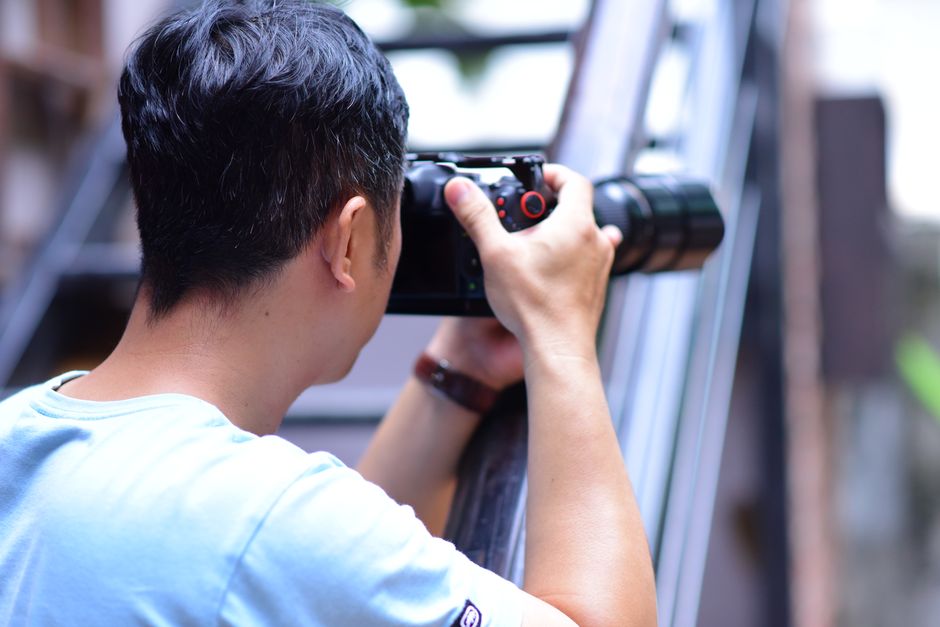 A photographer using a camera outside, focusing on capturing a scene.