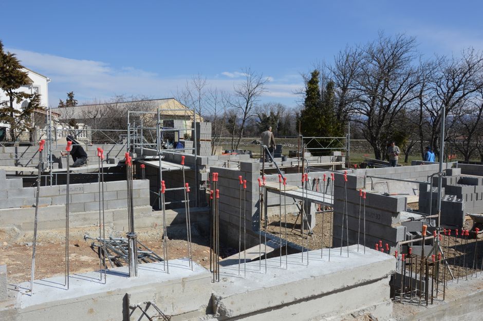Sunlit construction site with workers on concrete foundation under a clear blue sky.