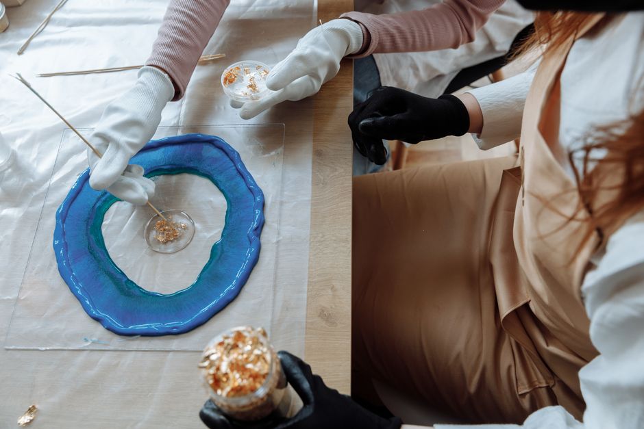 Hands crafting with resin and gold flakes, showcasing creative art techniques.