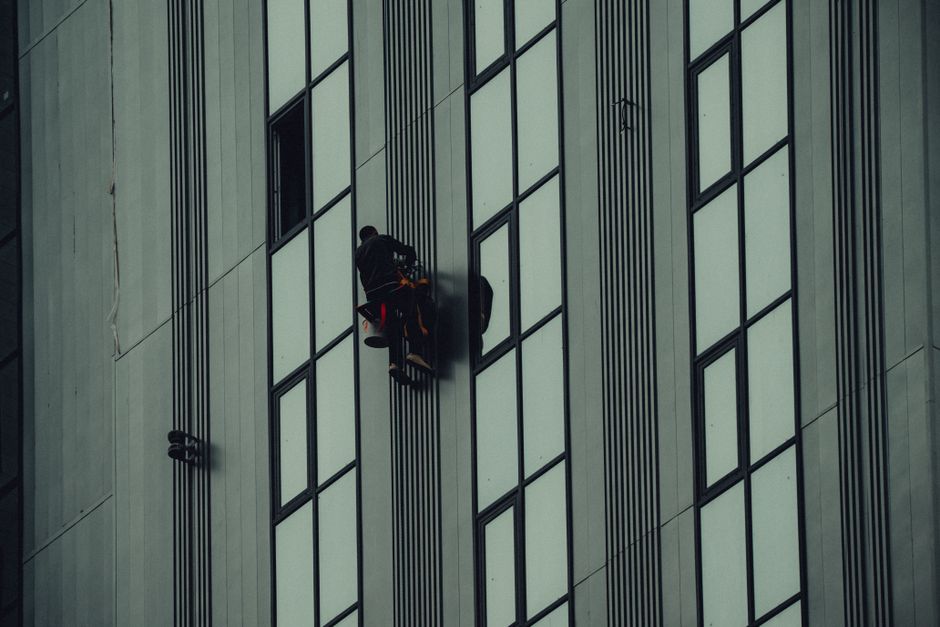 A window cleaner scales a tall building in Grozny, Chechnya, showcasing urban architecture.