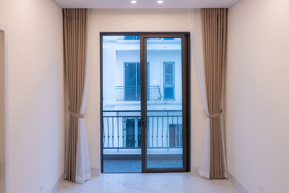 Interior view of a modern room featuring a large sliding glass door with elegant curtains.