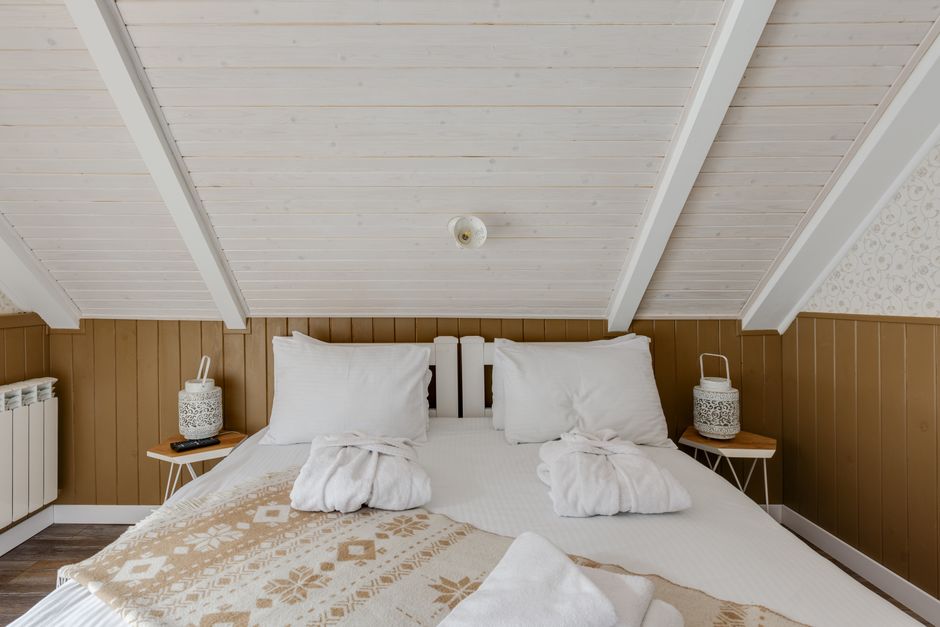 Inviting attic bedroom with cozy bedding and bathrobes on a white bed, perfect for relaxation.