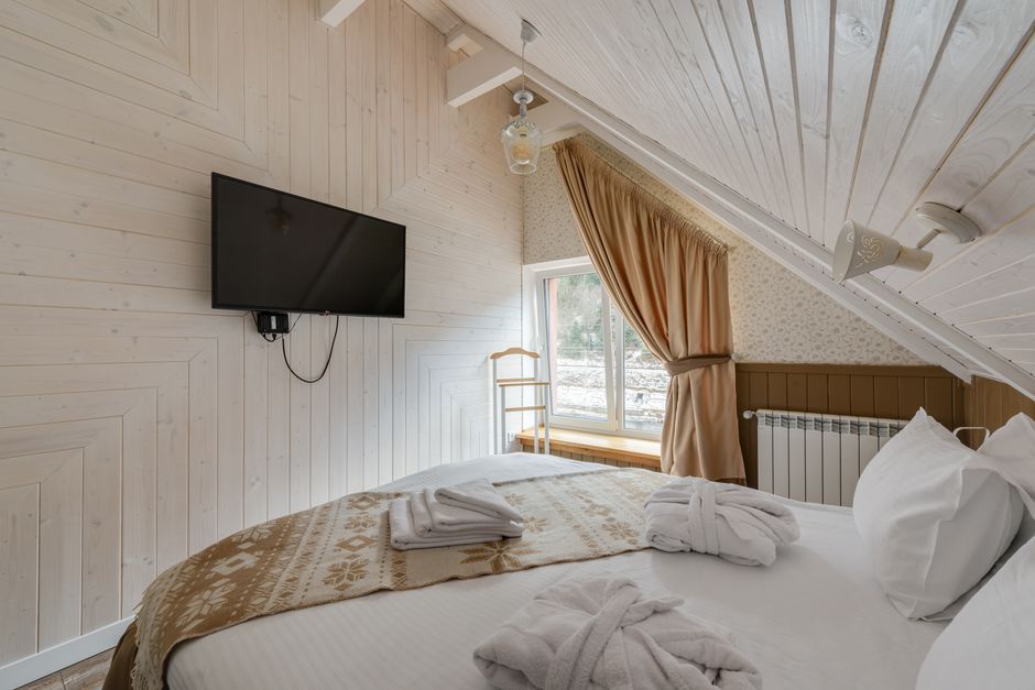 A serene attic bedroom featuring a modern TV and cozy decor, perfect for relaxation.