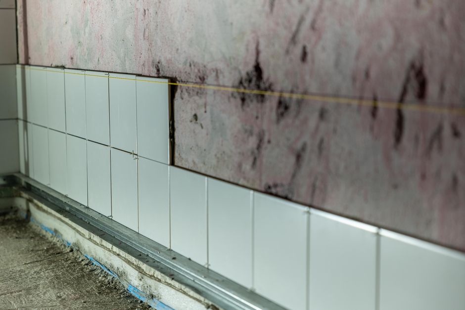Close-up of partially tiled wall in a construction area, showcasing incomplete renovation work.