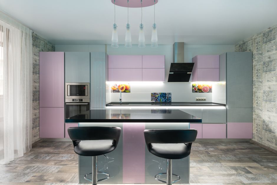 Spacious kitchen with black table and chairs placed near colorful cupboards and modern kitchenware in stylish apartment with window and tulle