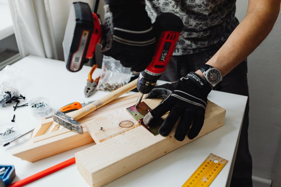 A craftsman uses a power drill on wood, showcasing carpentry tools and skills.