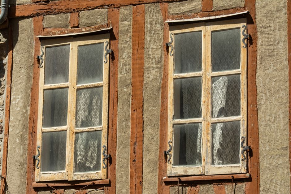 Close-up of rustic vintage windows with wooden frames on a traditional facade.