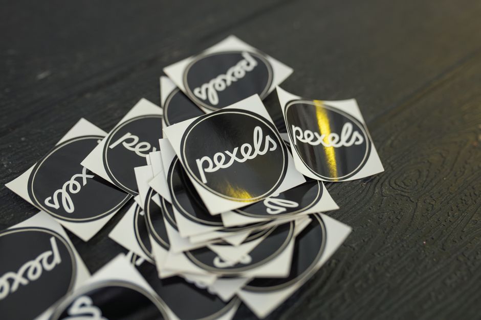 A collection of Pexels branded stickers scattered on a dark wooden surface.