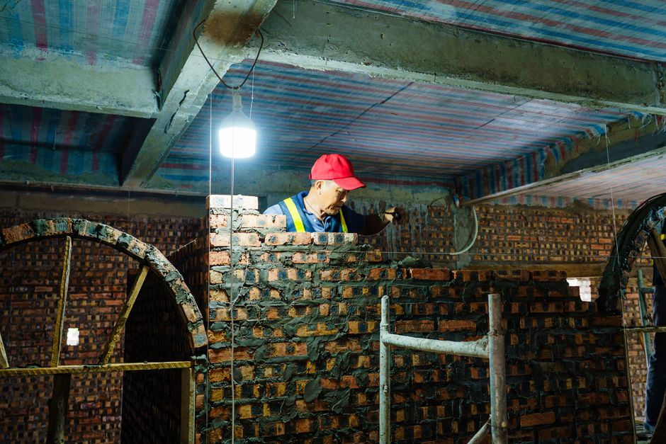 Skilled bricklayer building a wall at an indoor construction site in Hải Phòng, Vietnam.