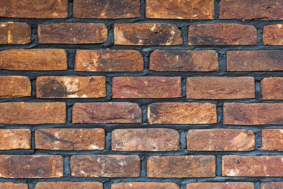 A detailed close-up view of a textured red brick wall with visible cement.