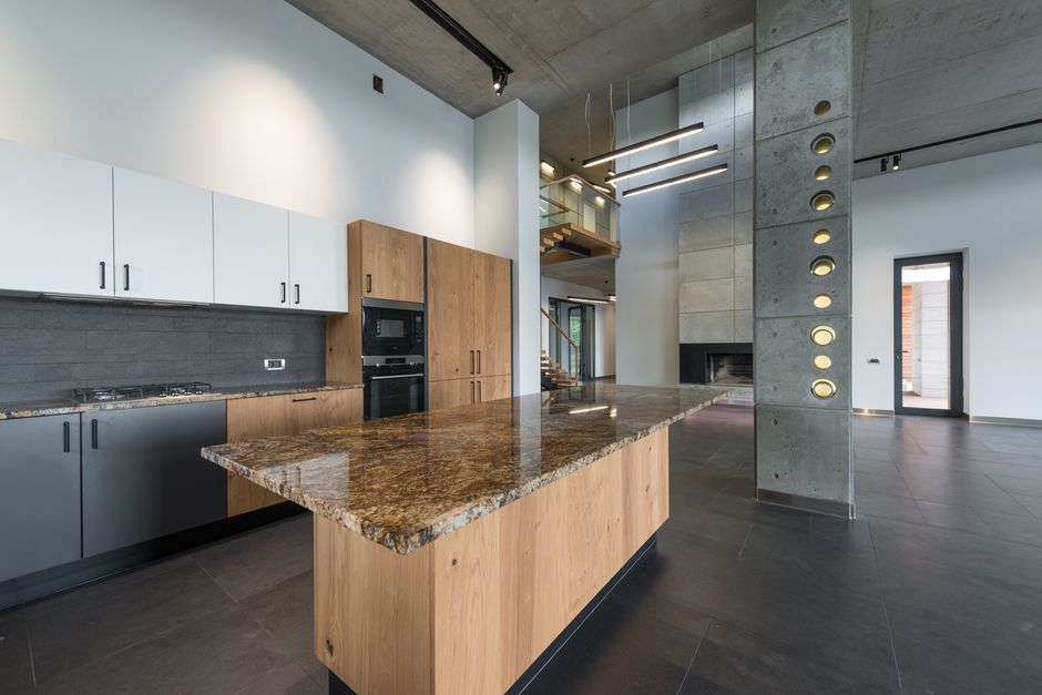 Spacious lobby with interior of modern kitchen with multicolored cabinets and wooden table in corner