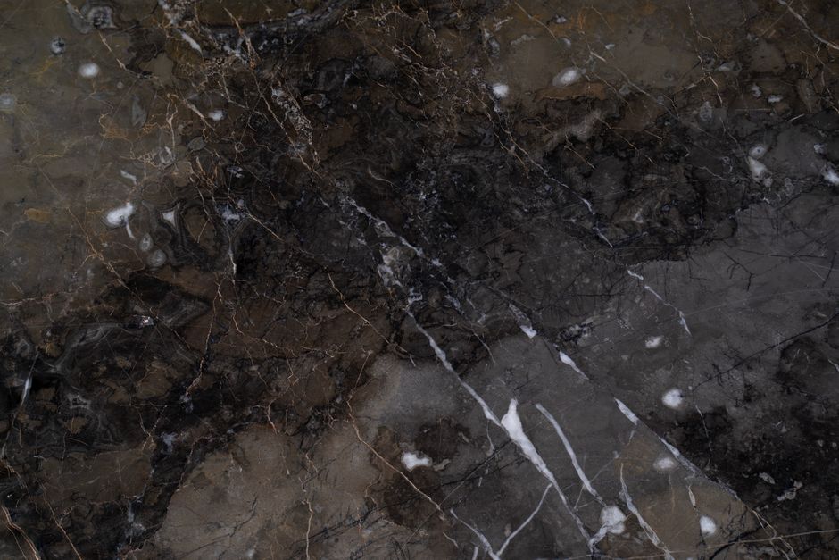 High-resolution image of a dark marble surface with intricate patterns and natural veining.