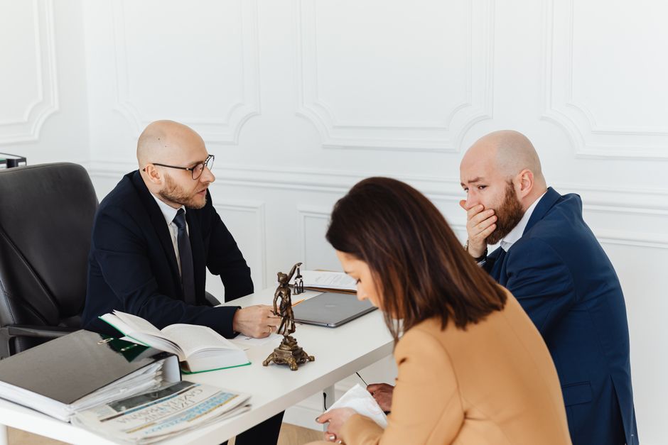 A serious legal consultation in a professional office environment involving three adults.