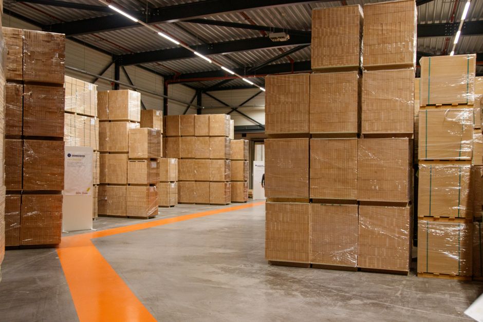 A spacious industrial warehouse filled with stacked cardboard boxes for storage and shipping.