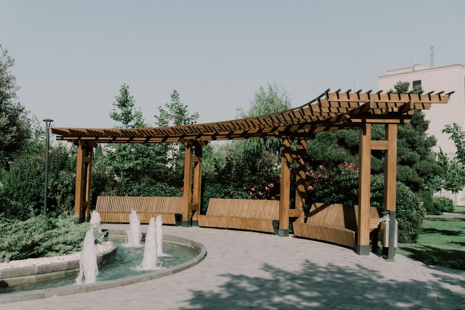 Serene park setting featuring a wooden pergola and fountains in Baku's White City.
