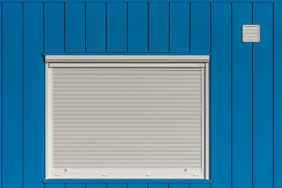 A modern blue wall with a closed white roller shutter, perfect for architectural designs.