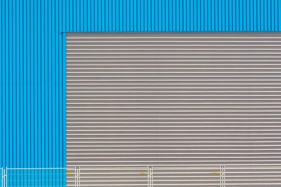 Blue industrial building facade with shutter door, showcasing modern architecture.