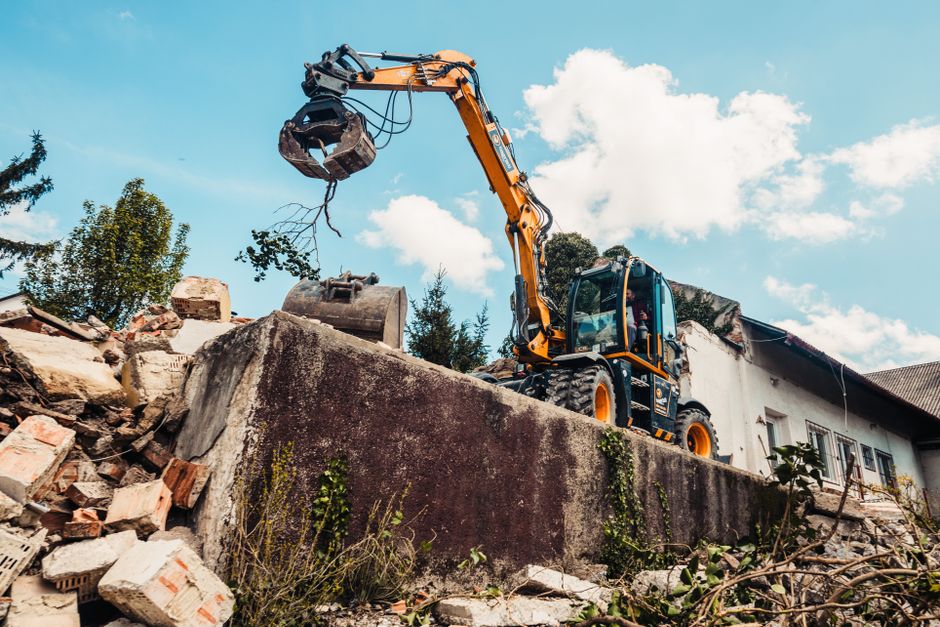 A bulldozer efficiently demolishing an old building, clearing rubble.