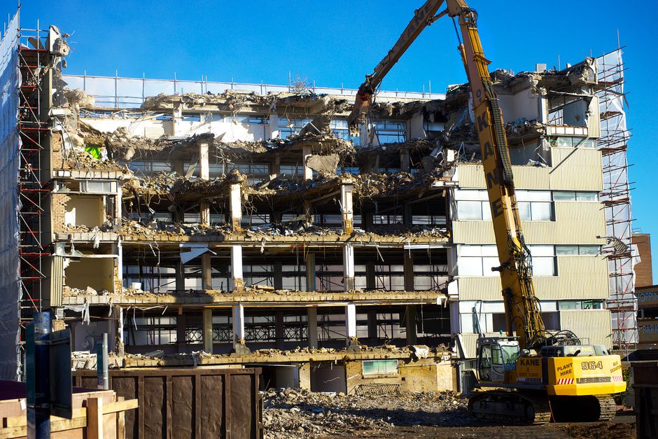 A building undergoing demolition with an excavator at work, capturing urban transformation.
