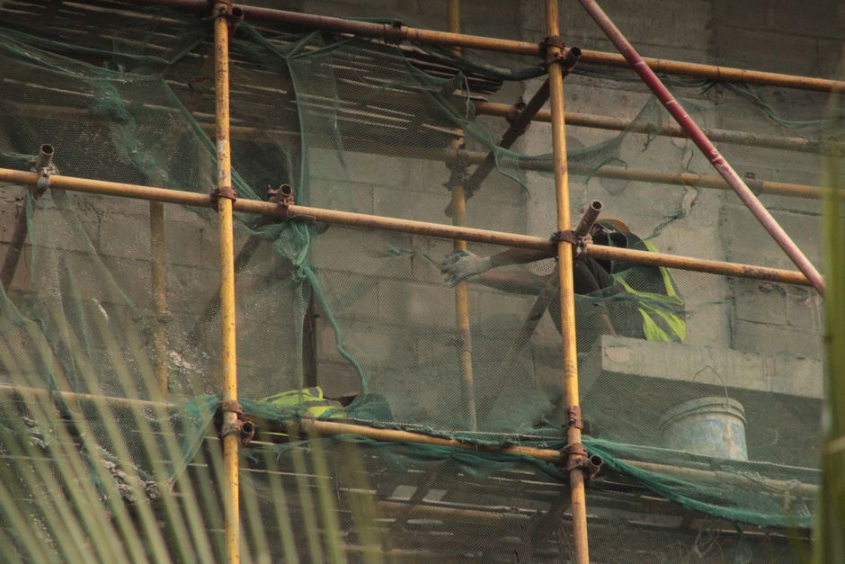 Workers on a building site, secured with scaffolding and safety netting.
