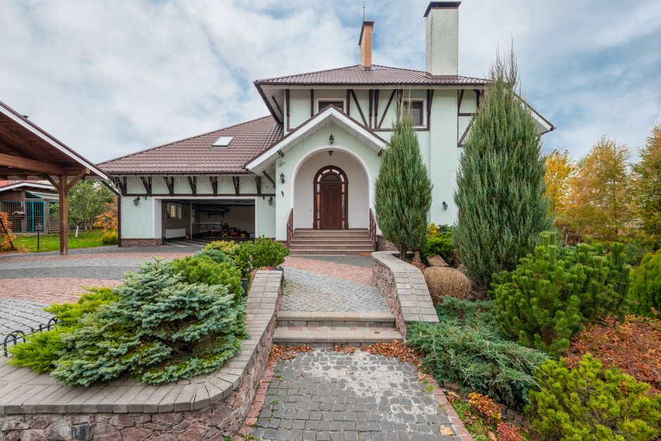 Elegant suburban house with decorative plants and paved driveway.