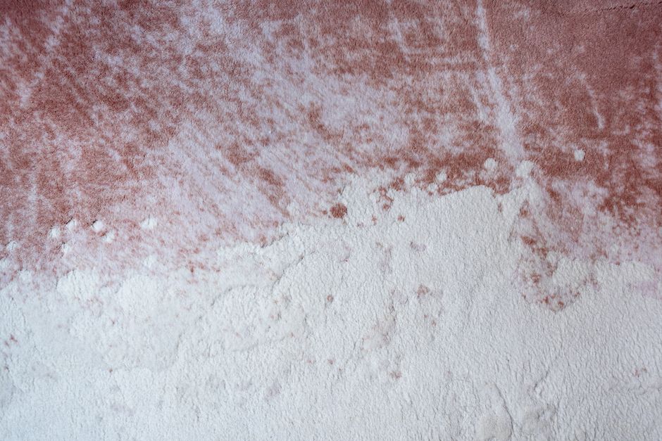Close-up abstract texture of a pink and white surface resembling plaster or paint.