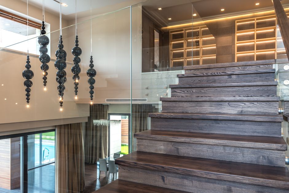 Elegant interior design featuring a wooden staircase with glass railing and artistic lighting.
