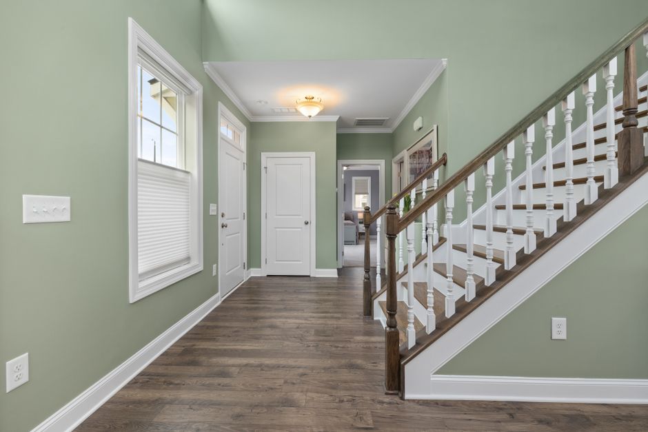 Spacious home interior featuring wooden stairs, green walls, and bright lighting. Ideal for modern living spaces.
