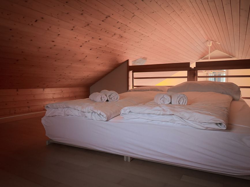 Warm, inviting loft bedroom featuring wooden ceiling and fresh linens.