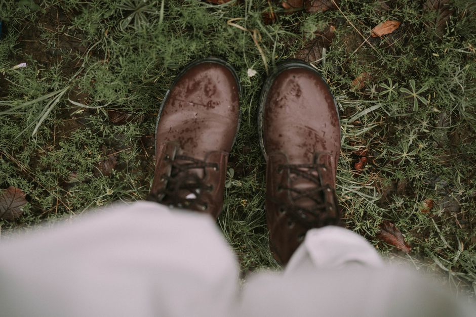 Top view of rain-soaked brown boots standing on lush green grass outdoors, showcasing a rugged style.