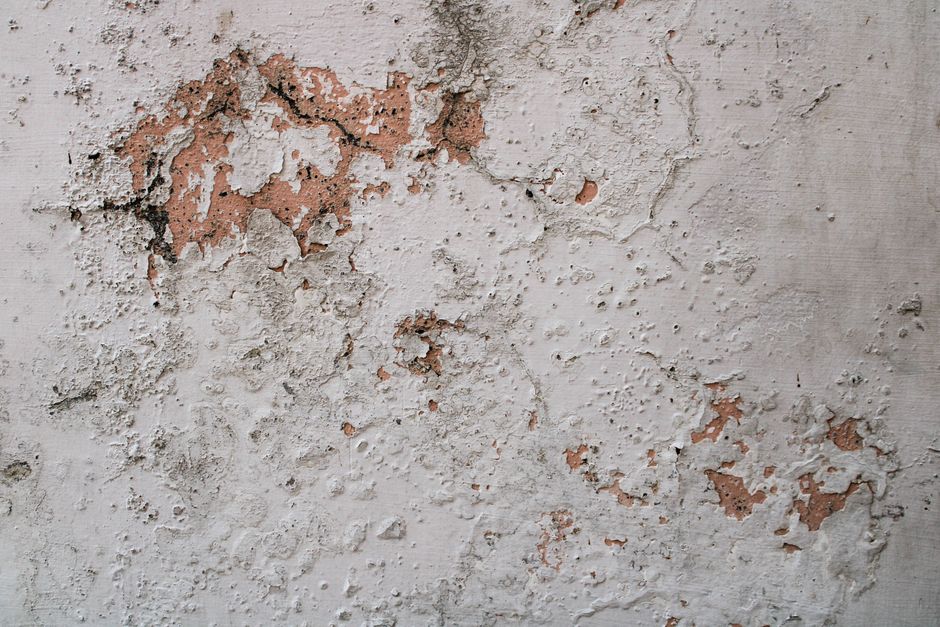 Detailed view of a weathered concrete wall with peeling paint and texture patterns.
