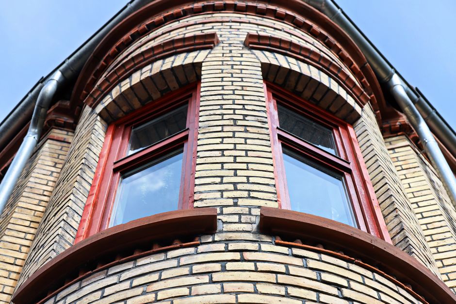 Detailed view of a brick building facade with red-framed arched windows.