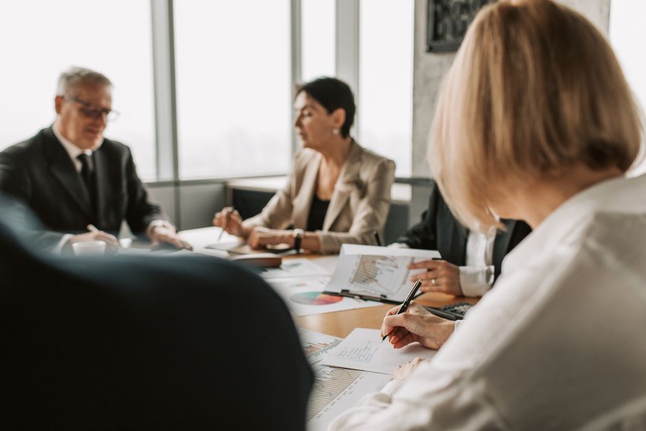 Colleagues discussing documents in a corporate office meeting.