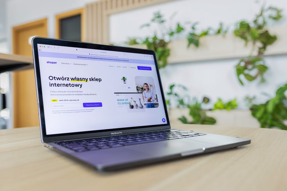 Close-up of a laptop with an open e-commerce website, surrounded by modern office decor.