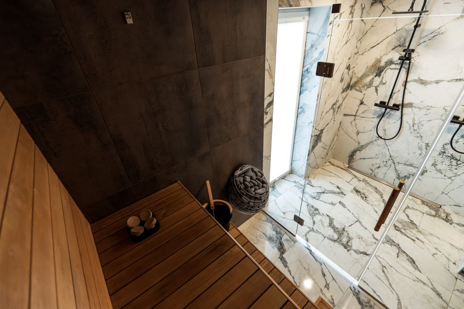 A contemporary sauna with a sleek design and adjacent marble shower, showcasing luxury indoor architecture.