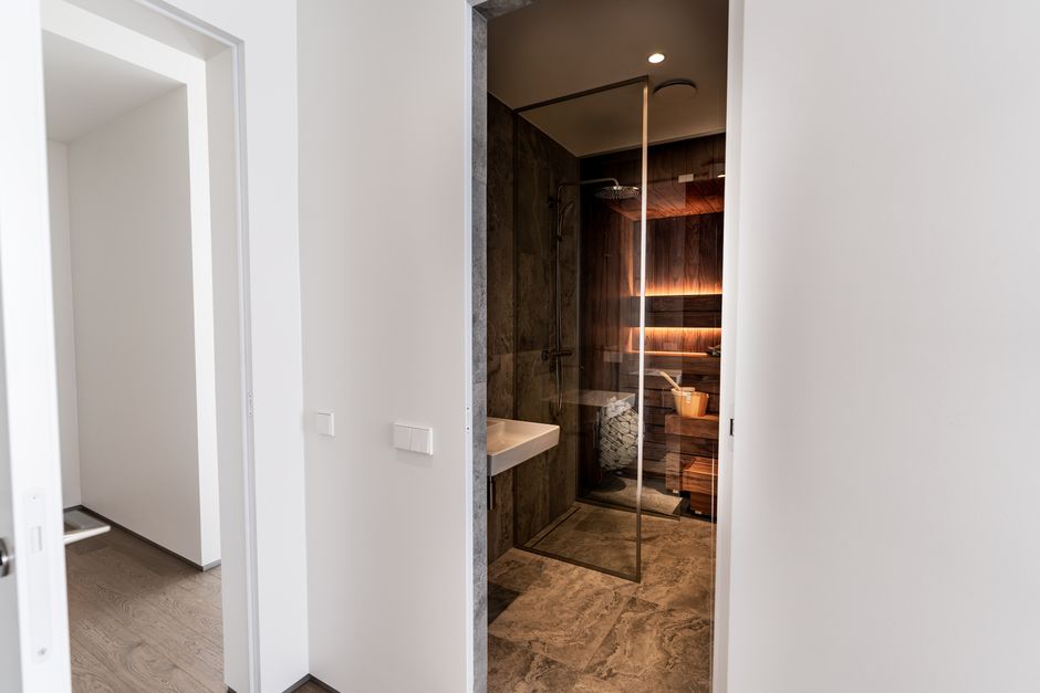 Stylish indoor sauna featuring a glass wall, wood panels, and a contemporary design for relaxation and wellness.