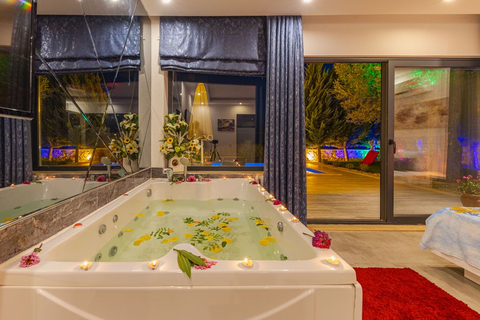 Experience ultimate relaxation in a luxury indoor jacuzzi adorned with petals and ambient candlelight, perfect for a serene retreat.
