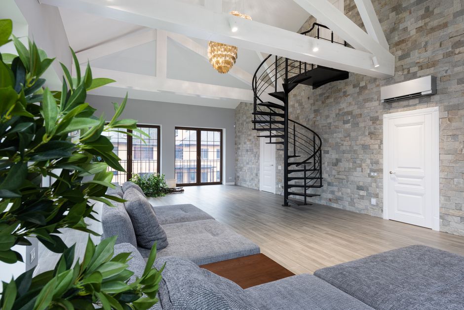 Interior of large prestige flat with soft gray sofa and verdant plants in daytime